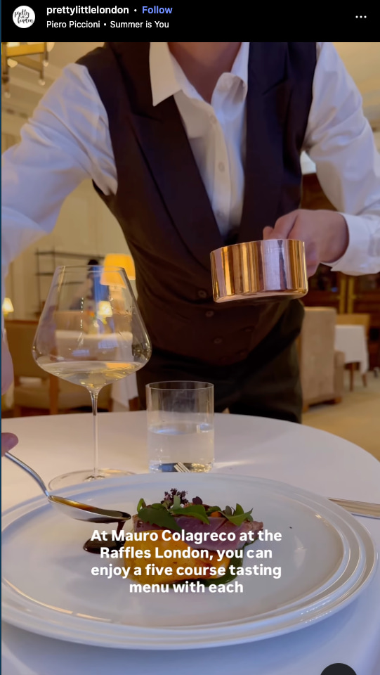 A server pours sauce over a fine-dining dish at Mauro Colagreco at Raffles London, with a wine glass and elegant table setting.