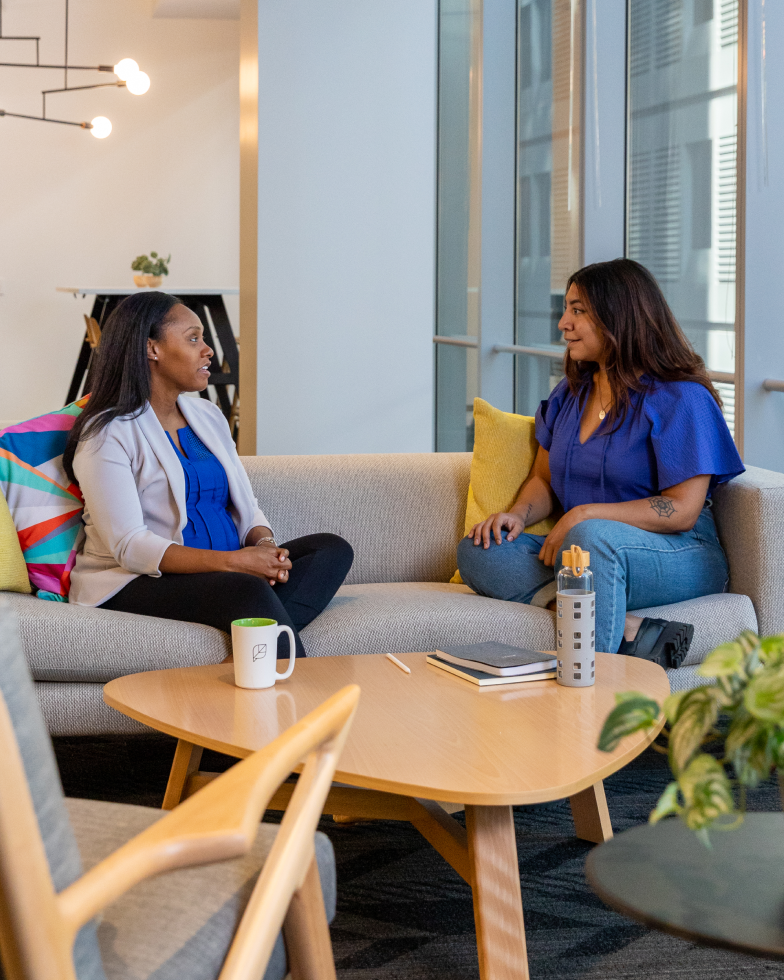 Two women of color sitting and engaging in dialogue.