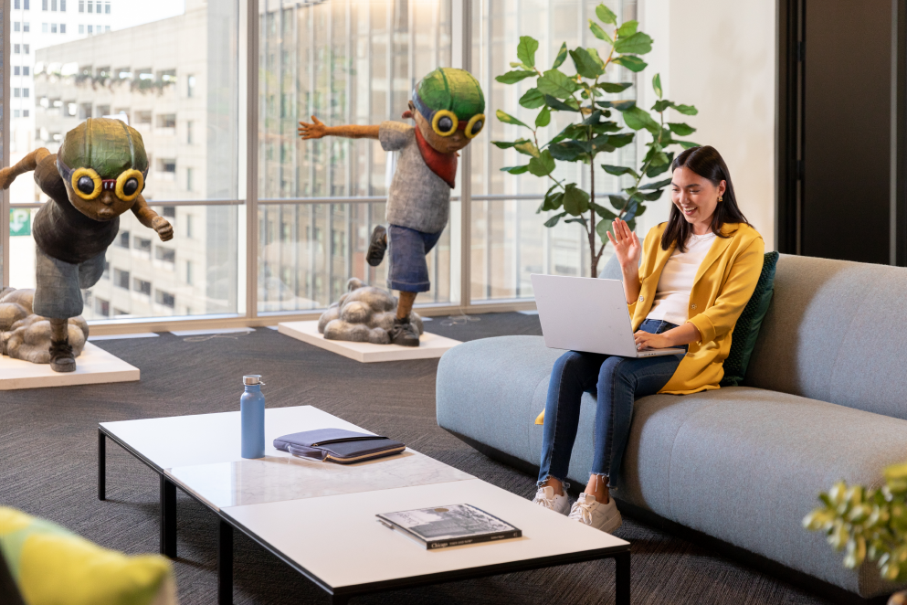  A femlate-identifying Sprout employee sits in one of our shared office spaces and waves during a virtual meeting.