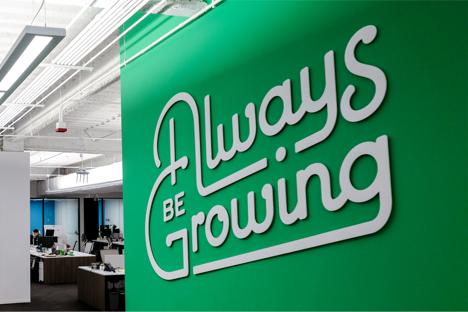  A green wall mural with the phrase “Always be growing” written in white, curvy typeface.